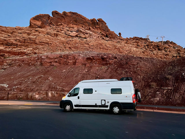 Experience travel freedom with an RV rental: White camper van beside stunning red rock mountains and a cable car.