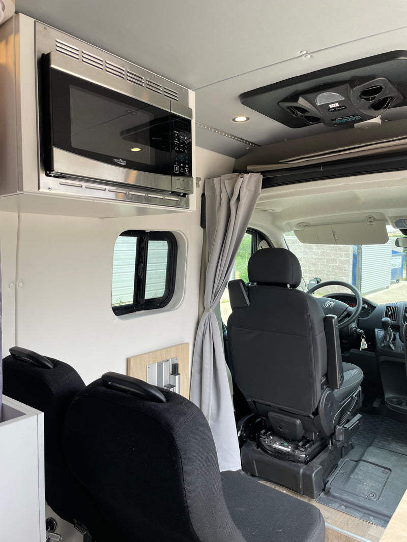 Modern RV rental interior showing microwave, passenger seats, and ceiling cooling unit, ready for adventures. — photo 18