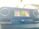 Inside an RV rental: Dashboard infotainment screen displays a 360° camera view, aiding parking by showing the vehicle and its surroundings.