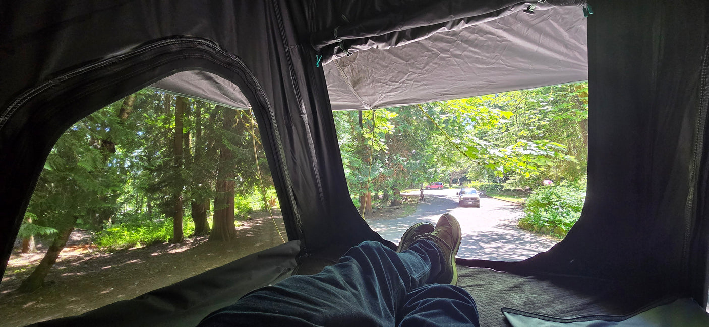 Relaxing in an RV rental, feet up, enjoying green trees & a road with cars & a cyclist. A great camp view.