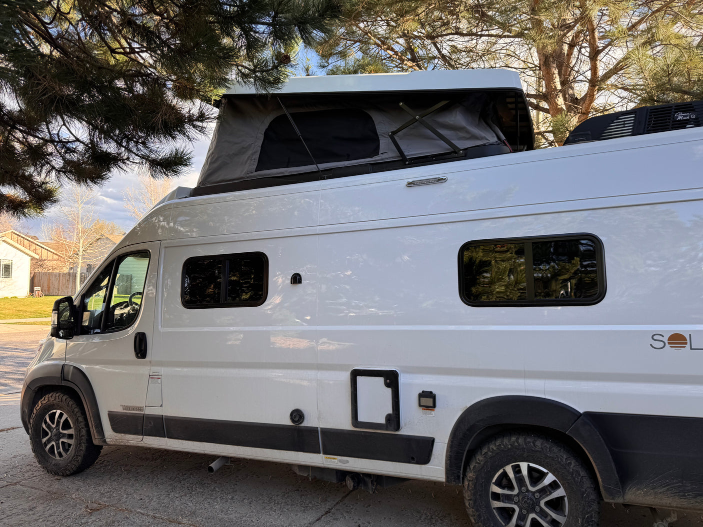This white Winnebago Solis camper van, featuring a pop-top roof tent, is an ideal rv rental for outdoor adventures.