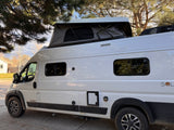 This white Winnebago Solis camper van, featuring a pop-top roof tent, is an ideal rv rental for outdoor adventures.
