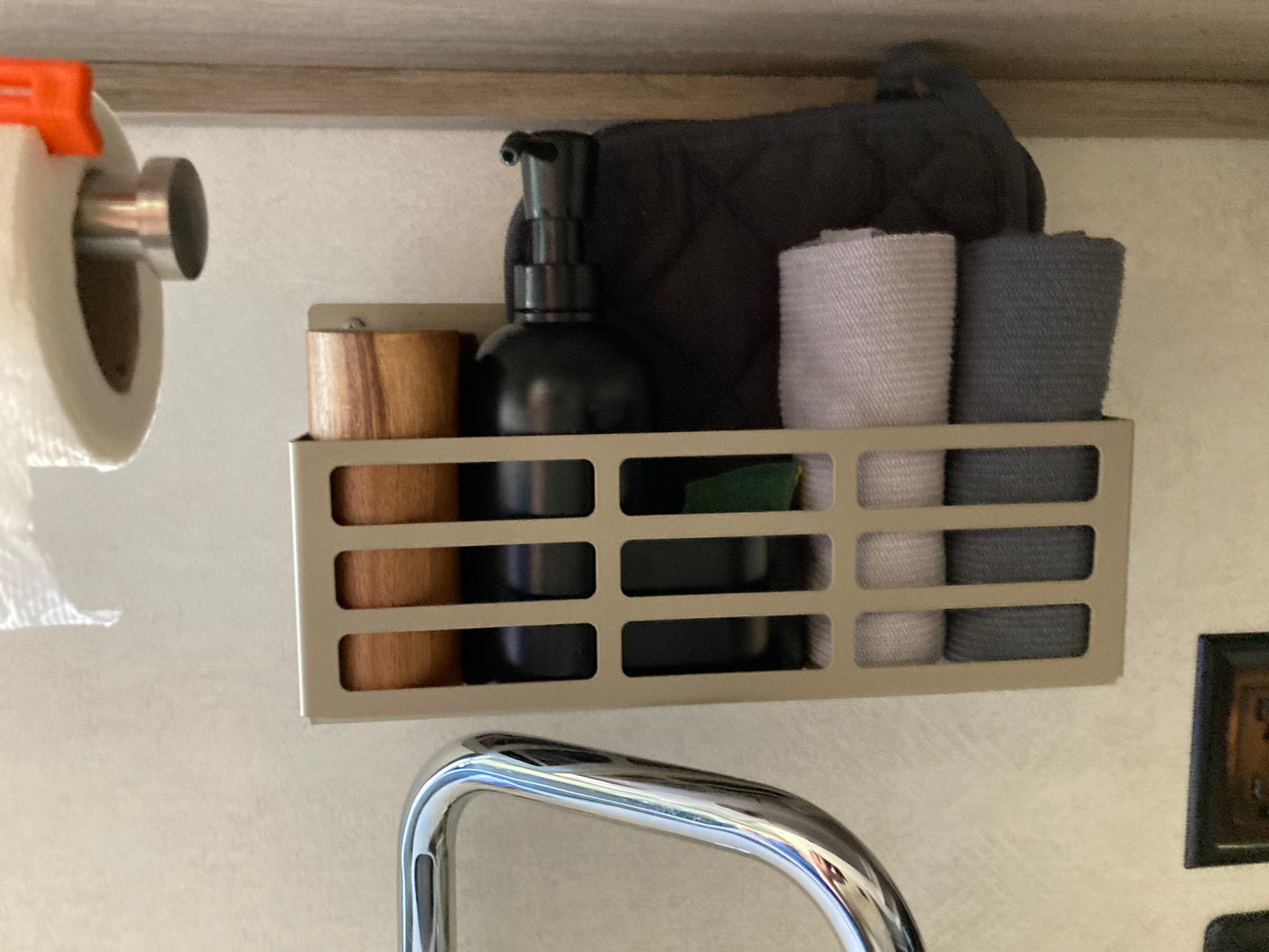RV rental amenities: Organized sink area with soap, towels, paper towel, and cooking mitt in a compact caddy.