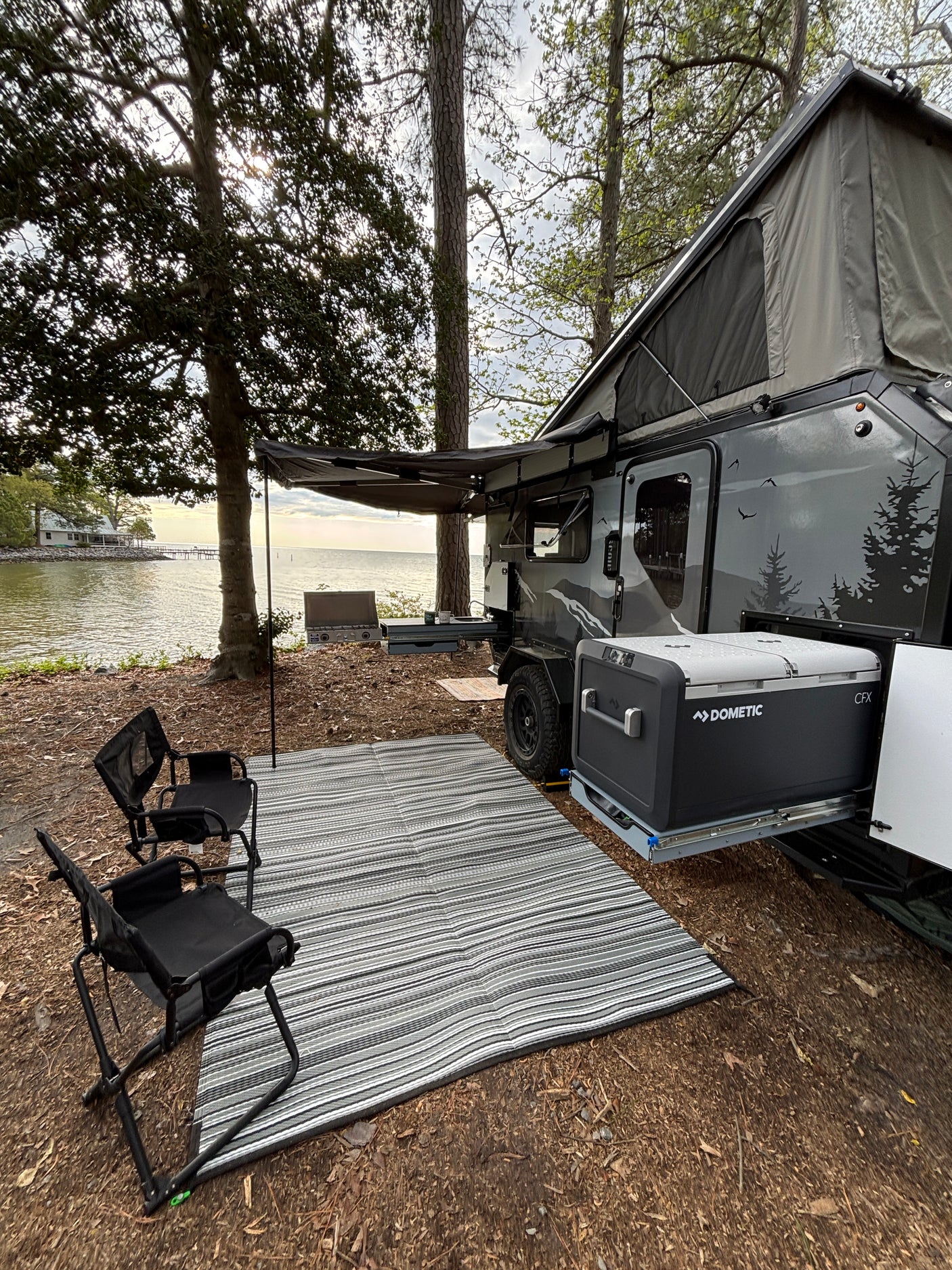 Waterfront RV rental setup with Dometic cooler, awning, and chairs. Perfect for camping by the lake or bay.
