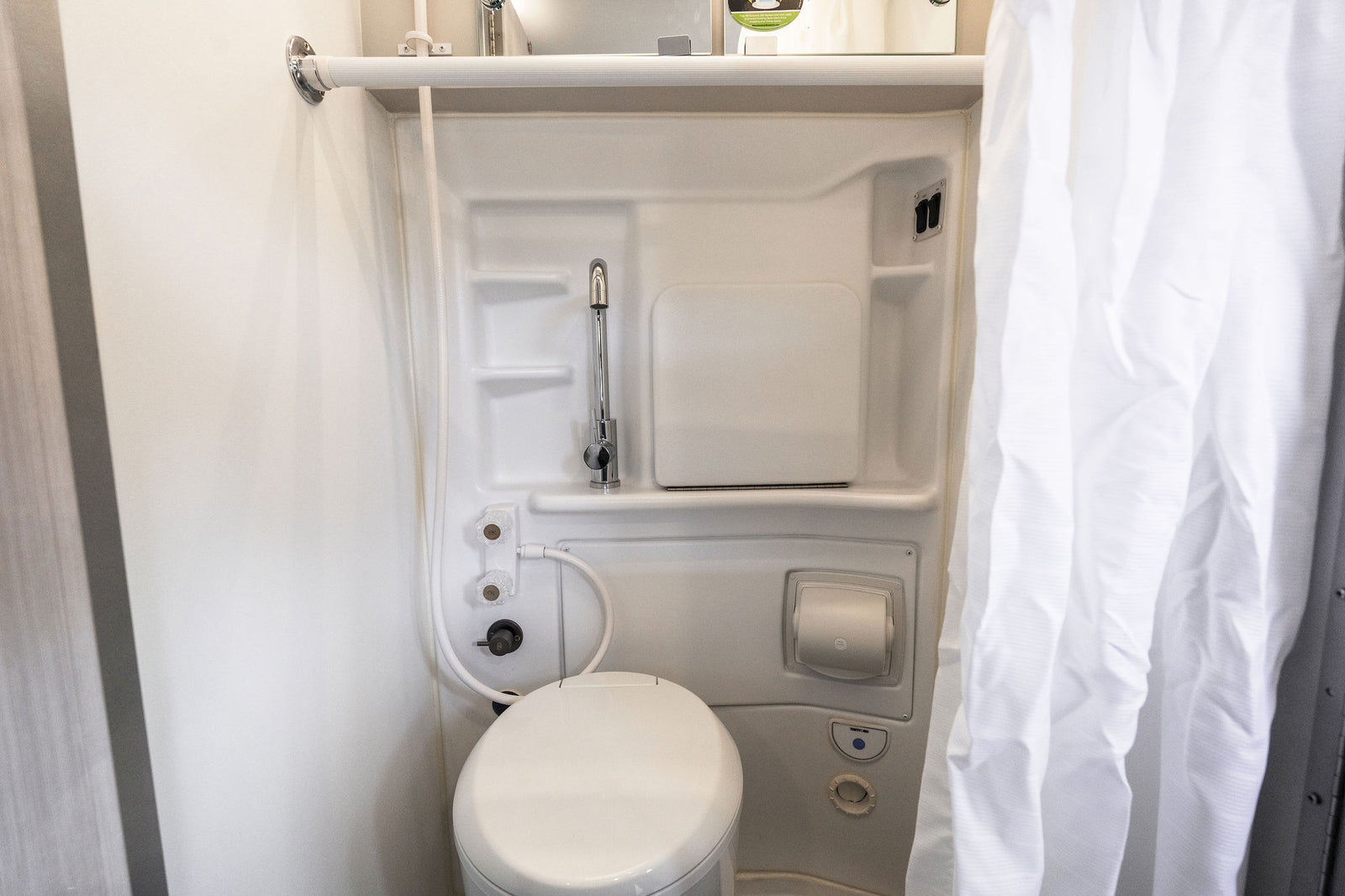 This RV rental features a clean, compact wet bath with a toilet, versatile faucet/shower, & privacy curtain.