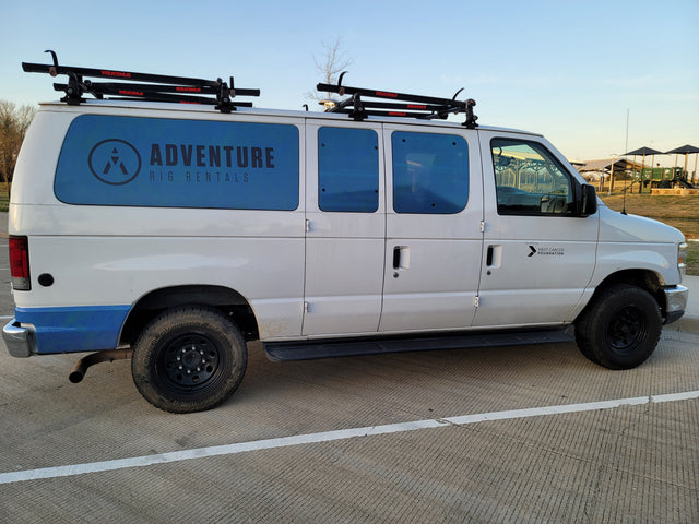 White "Adventure Rig Rentals" van, an RV rental, with Yakima roof racks, benefiting West Cancer Foundation.
