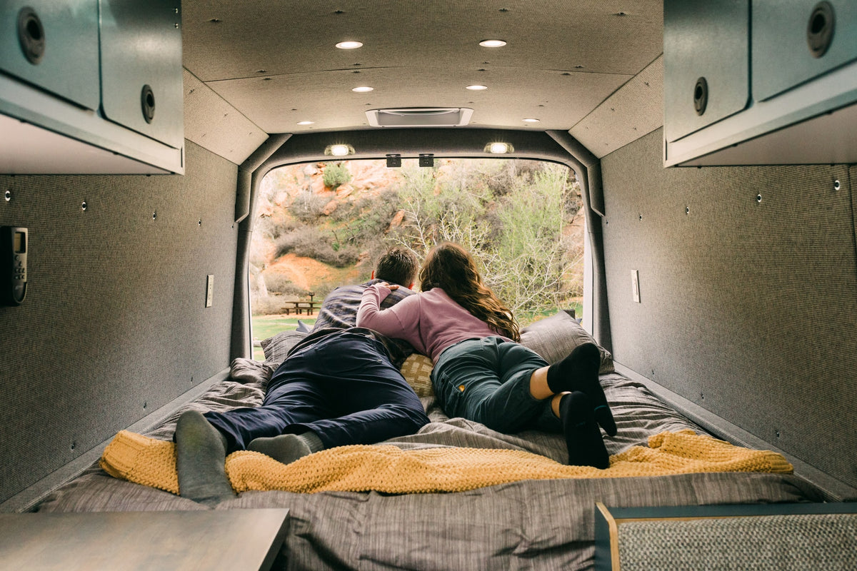 Couple enjoys serene nature views from their RV rental's cozy bed. Experience comfort and adventure on the road. — photo 4