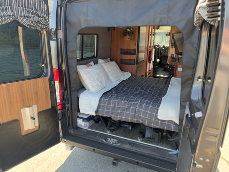 Step inside this cozy RV rental: a comfortable bed and functional living area await your next road trip.