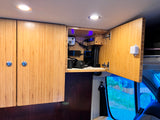 RV rental: Organized camper van interior featuring overhead bamboo cabinets, a charging station for camera gear, and LED lights.
