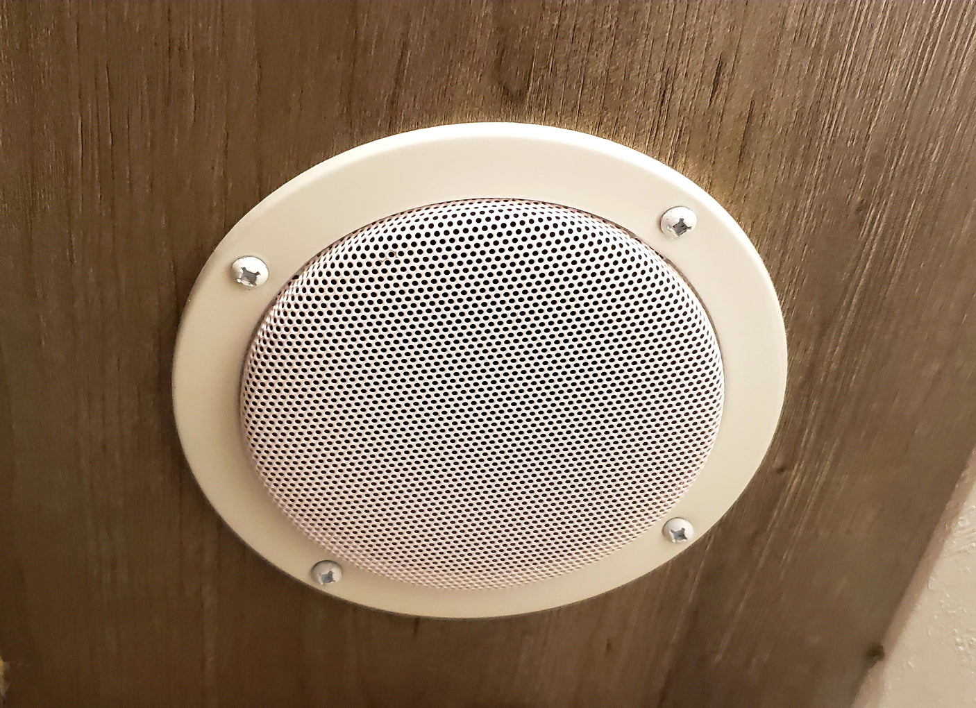 Circular beige speaker or vent with a perforated grille, mounted on wood paneling inside an RV rental.