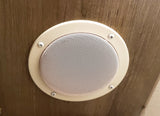 Circular beige speaker or vent with a perforated grille, mounted on wood paneling inside an RV rental.