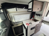 Compact camper van rv rental interior with a kitchenette, sink, overhead storage, and window, optimized for travel.