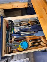 A well-organized kitchen drawer in an RV rental, stocked with silverware, cooking tools, and even a camping fork.