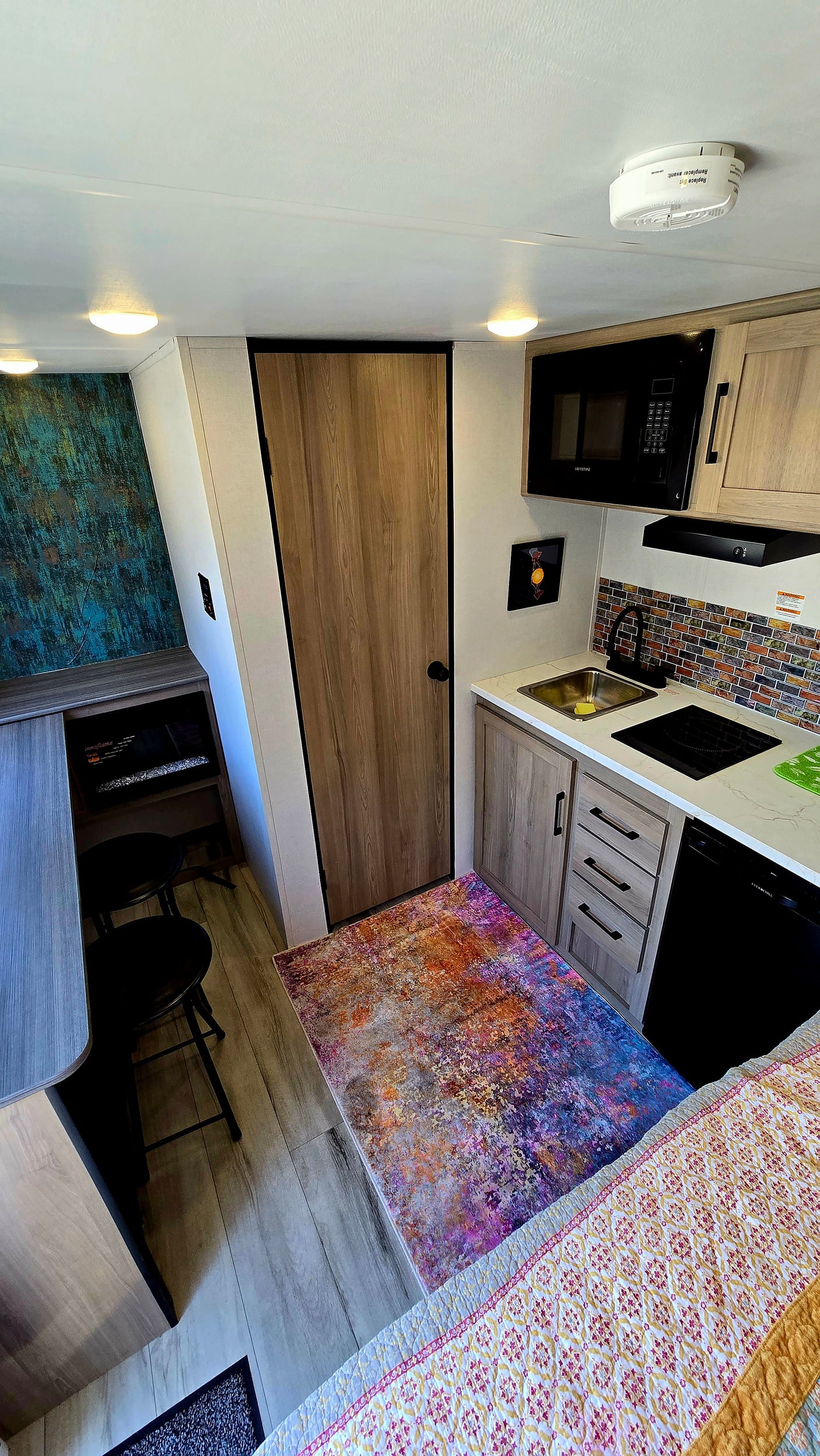 Cozy RV rental interior showcasing a functional kitchen, dining nook with a fireplace, and vibrant decor for comfortable travel.