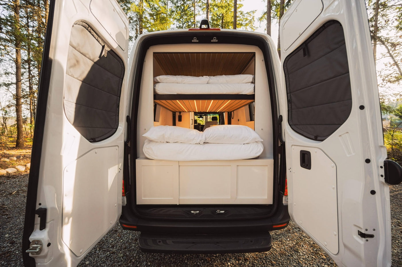 This RV rental's rear doors open to a well-lit interior with comfy bunk beds, ready for travel. — photo 8