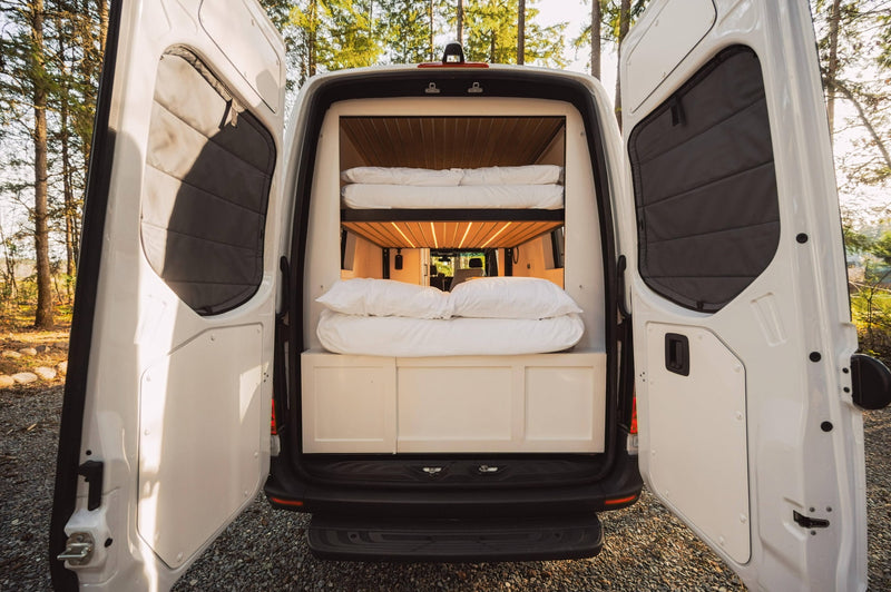 This RV rental's rear doors open to a well-lit interior with comfy bunk beds, ready for travel. — photo 8