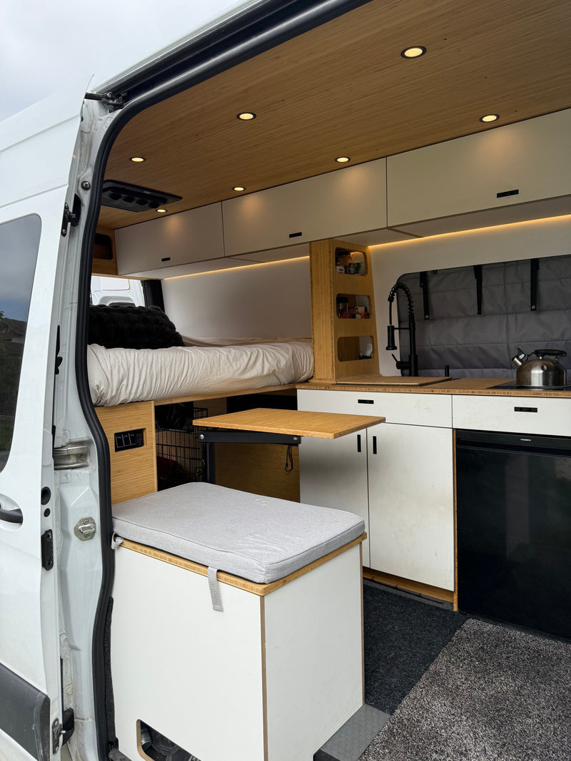 This RV rental shows a modern camper van interior with a bed, kitchen, and pull-out table, optimized for comfortable travel. — photo 4