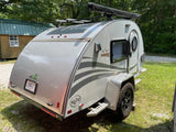 A modern, silver nuCamp T@G Boondock teardrop trailer, equipped with off-road tires, an excellent choice for RV rental camping.