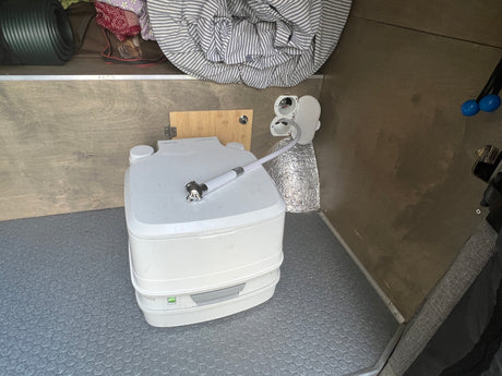 RV rental: Compact interior showing a portable toilet with sprayer, offering essential sanitation for travel.