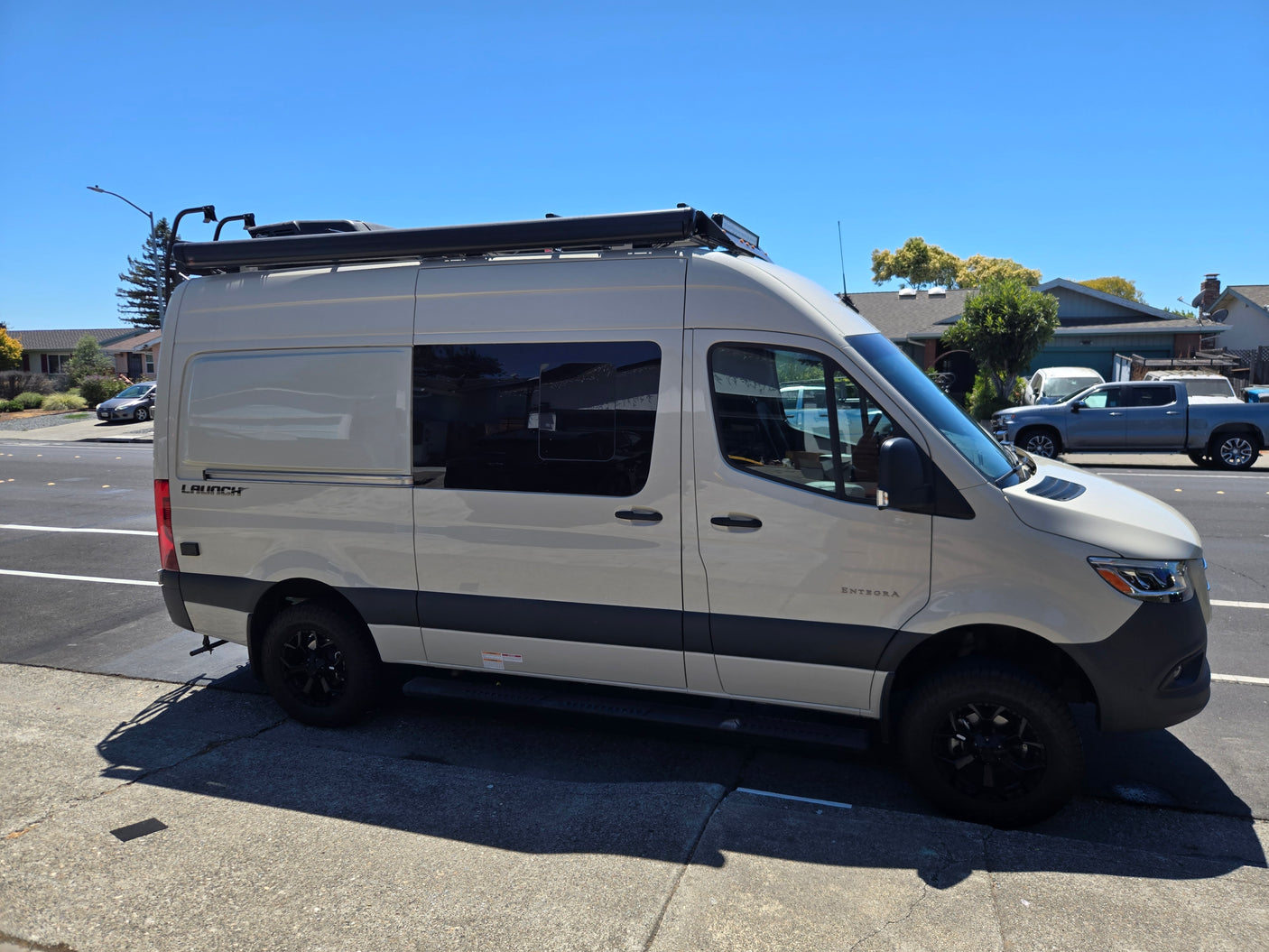 Customized light-colored camper van with a roof rack and awning, perfect for your next RV rental trip.