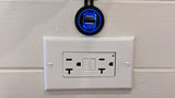 Dual USB charger (5V 2.1A) and GFCI electrical outlet on a textured wall in an RV rental.