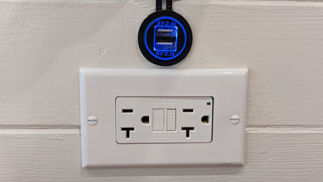 Dual USB charger (5V 2.1A) and GFCI electrical outlet on a textured wall in an RV rental.