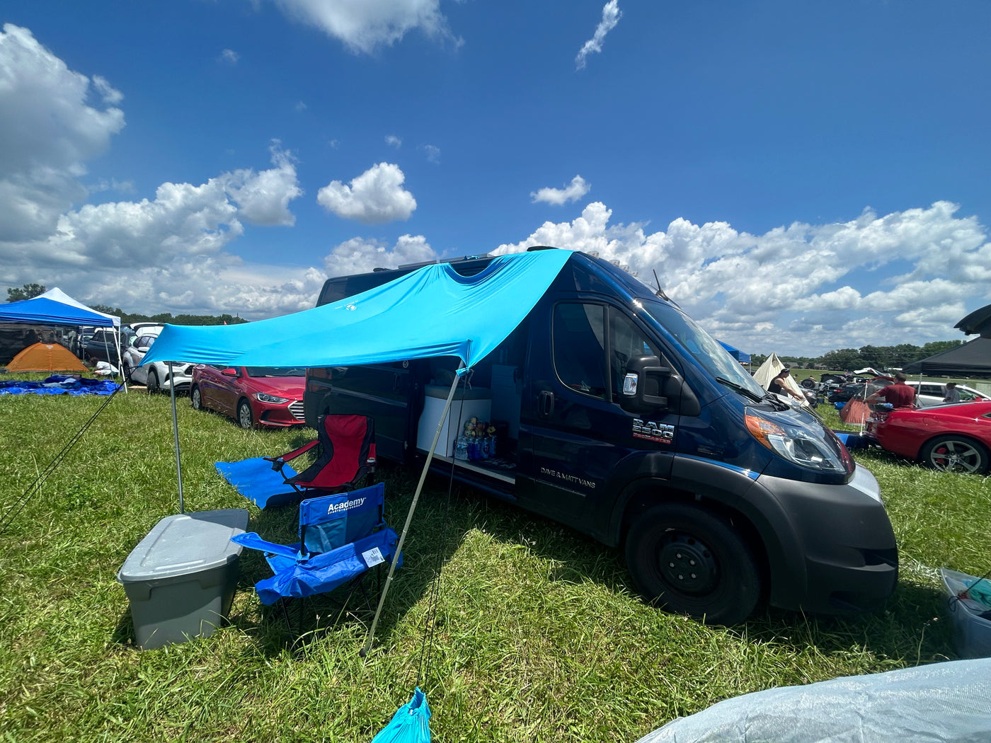 Blue RV rental van with a bright shade awning, set up in a grassy field. Perfect for outdoor camping and adventures. — photo 8