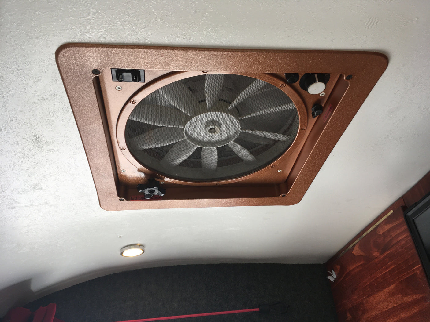 RV rental: Ceiling fan with screen on a textured white ceiling. Controls for airflow direction (in/out), speed, and lid.