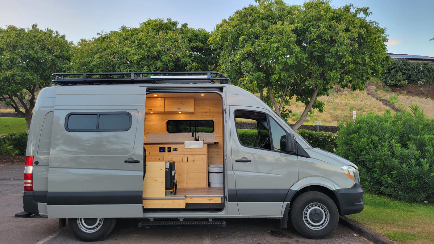 Custom camper van for rv rental, showcasing a comfortable wood interior with a functional kitchen and toilet.