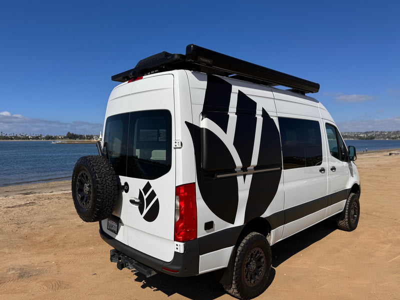 Explore the outdoors with this white RV rental camper van, featuring custom graphics, parked on a sandy beach near the water. — photo 36