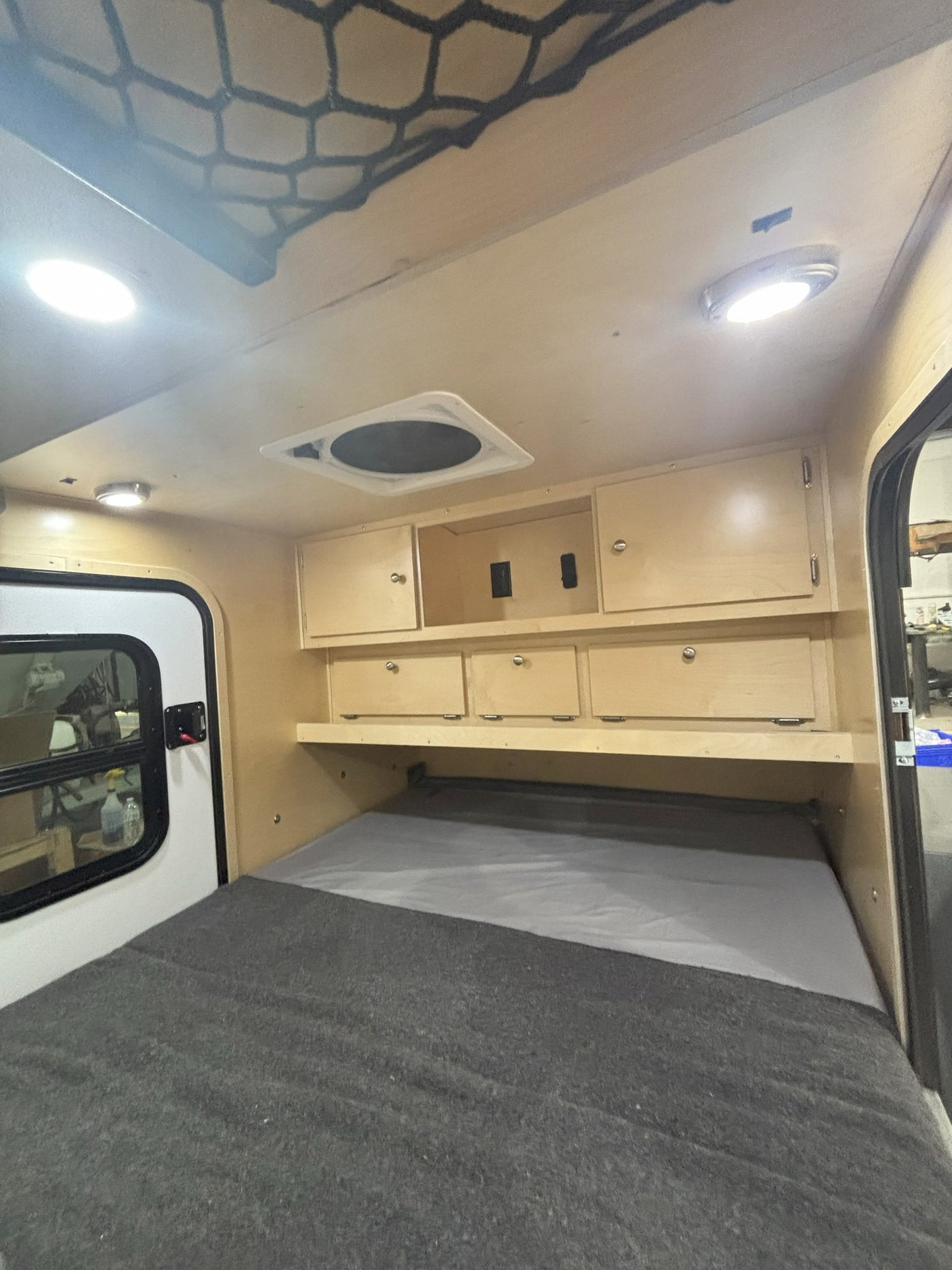 RV rental's cozy interior: features a bed, wooden cabinets, ceiling lights, and a fan, ready for your next adventure. — photo 6