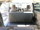 RV rental interior: View from rear of vehicle showing a large, grey custom storage unit replacing middle seats, with front cabin visible.