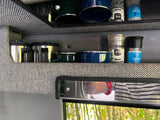 Neatly organized kitchen supplies, including mugs & spice grinders, in an RV rental for road trips and camping.