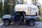 Gray Toyota Tacoma with a Kimbo truck camper attached, ideal for an RV rental outdoor adventure or camping trip.