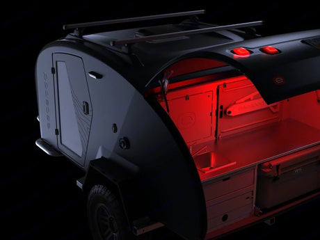 Sleek, dark teardrop camper for RV rental, showing its red-lit rear kitchen with sink, drawers, and YETI cooler.