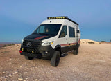 A custom white/black Mercedes Sprinter camper van, equipped for off-road rv rental trips, on a gravelly desert overlook.