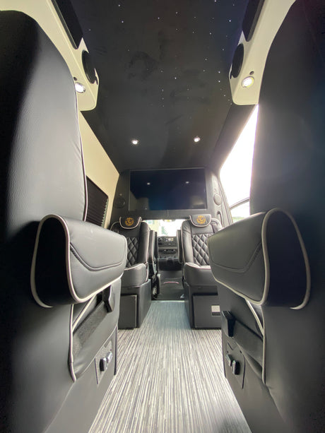 Explore this luxury RV rental's interior: plush seating, large entertainment screen, and starlight ceiling. Perfect for comfortable journeys.