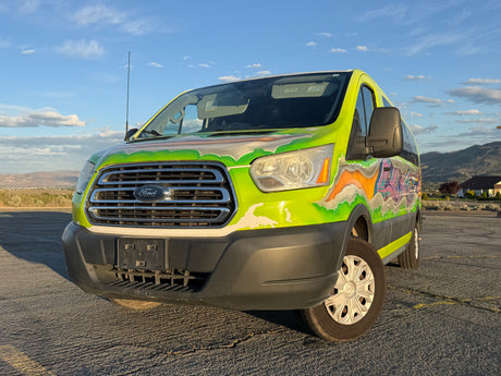 This custom-painted Ford Transit van, an eye-catching rv rental, features vibrant graffiti art, parked against a scenic mountain backdrop.