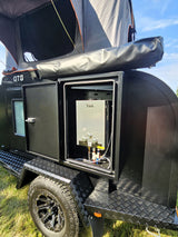Black OTG teardrop RV rental featuring an external Yink water heater and rooftop tent. Ready for adventure.