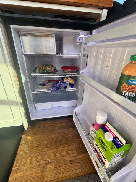 Open compact Isotherm fridge in an rv rental, holding almond milk, stir-fry, and taco ranch.