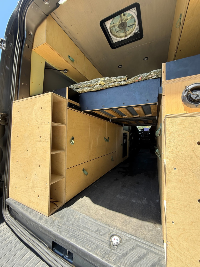 This custom-built plywood RV rental interior offers a bed, storage, and ceiling fan for comfortable travel. — photo 7