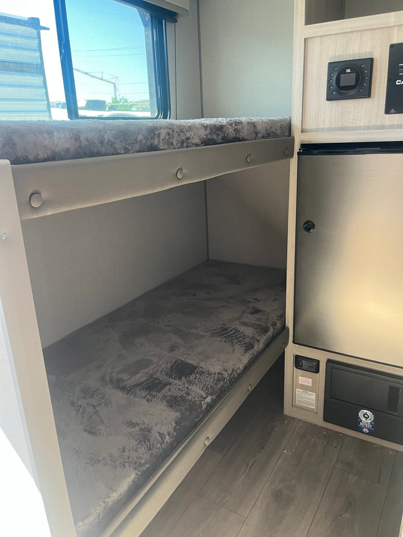 This RV rental features a cozy bunk bed sleeping area, integrated refrigerator, and JBL control panel for comfort on the road. — photo 9