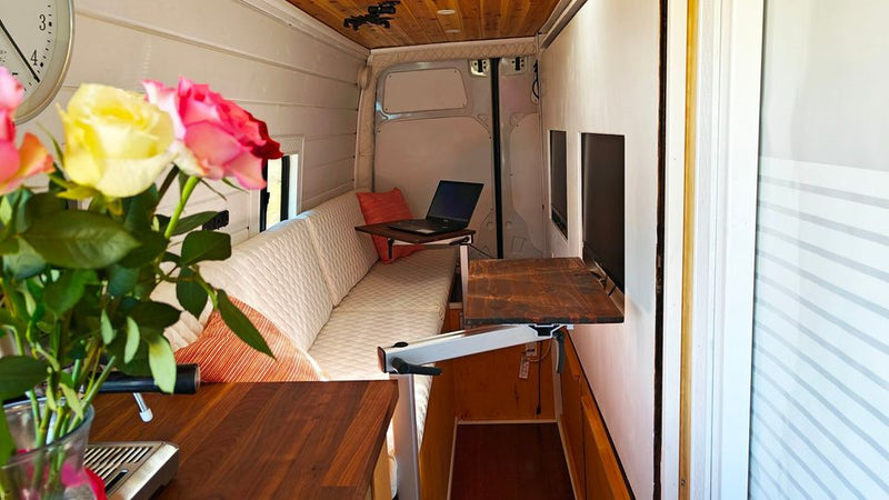  is parked by a lake amidst dry grass and hills under a clear sky.|RV rental: Enjoy van life with this mobile office setup inside — photo 6