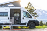 White pop-top camper van rv rental, open side, outdoor table, and majestic mountains for your adventure.