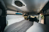 An RV rental's cozy interior looking forward, showing a bed, storage, and front cabin view for travel adventures.