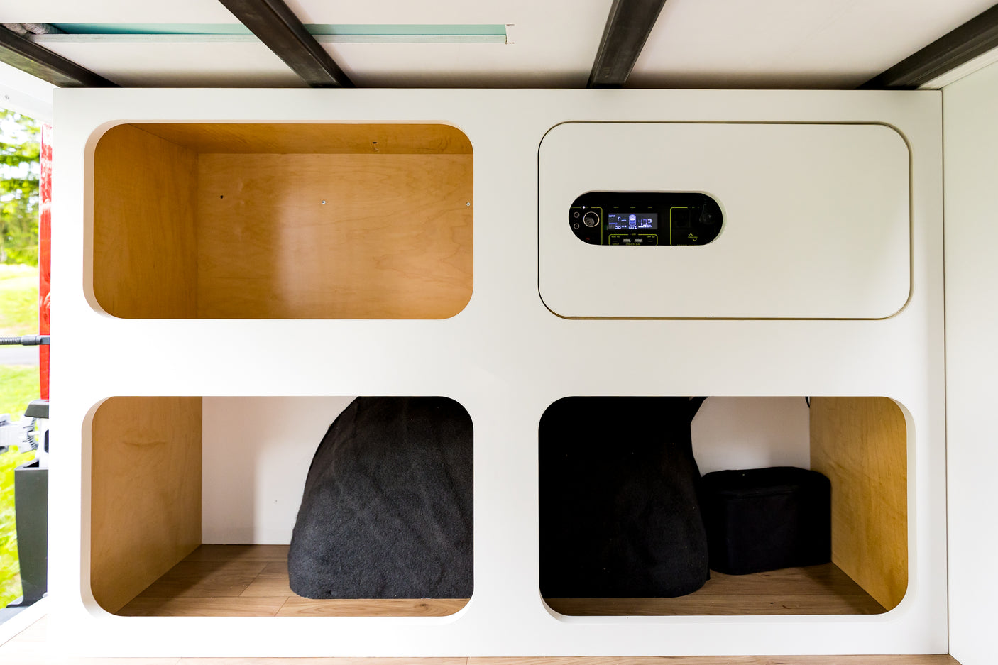 RV rental interior: Sleek white cabinets, wooden storage cubbies, and a portable power station for your camper van adventures.