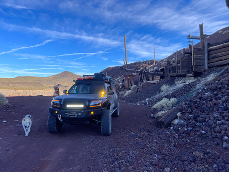 An off-road truck, person, and dog at a historic desert mining site. A rugged alternative to typical RV rental exploration.