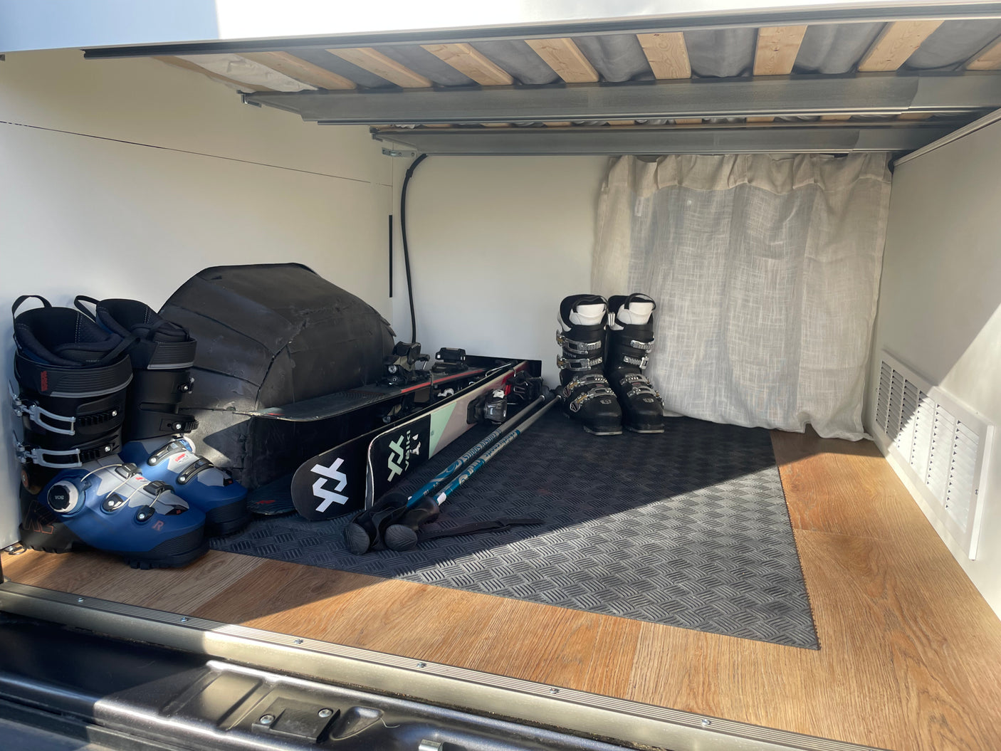 RV rental storage with ski boots, skis, and poles in a campervan garage. Perfect for winter sports adventures and travel.