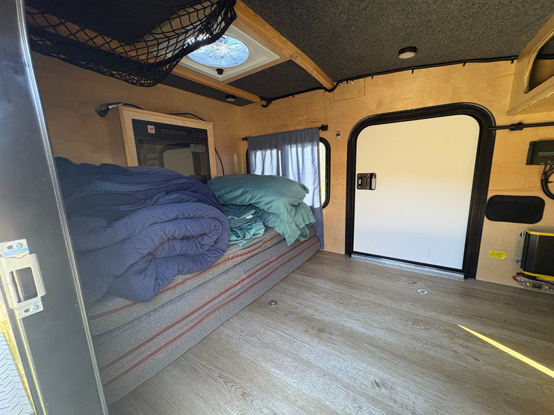  enjoying a rugged outdoor camping trip.|This RV rental interior features a cozy bed — photo 5