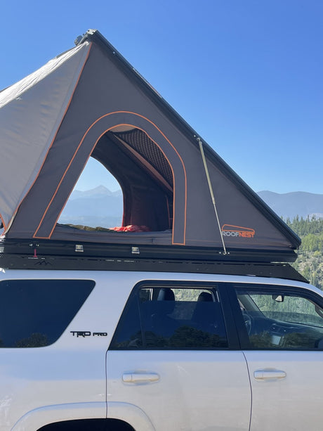 Experience camping freedom! This white 4Runner with a deployed Roofnest rooftop tent offers a unique RV rental alternative.